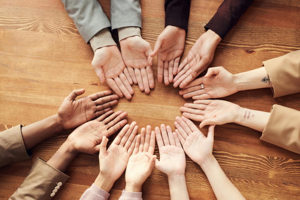 pexels photo 3184397 3184397 Top view of diverse hands forming a circle on a wooden table, symbolizing unity and diversity.