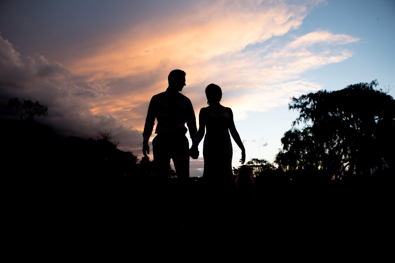 Silhouette of a couple holding hands under a vibrant sunset sky, creating a romantic and serene atmosphere.